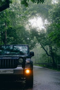 A jeep on a misty road through lush Kerala forest, perfect for adventure travel.