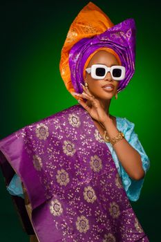 Woman in colorful Nigerian traditional attire with bold accessories and vibrant fabrics.