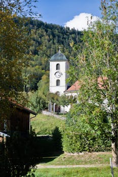 A charming church tower amidst lush greenery in the Swiss countryside.