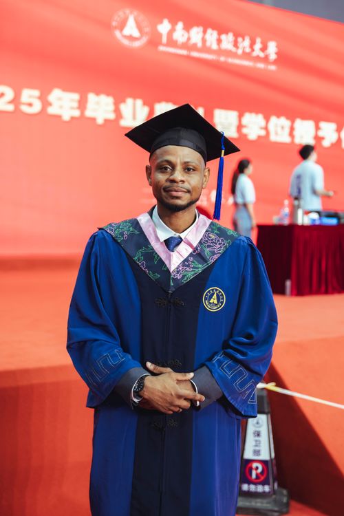 Free A proud graduate in cap and gown with an academic setting backdrop. Stock Photo