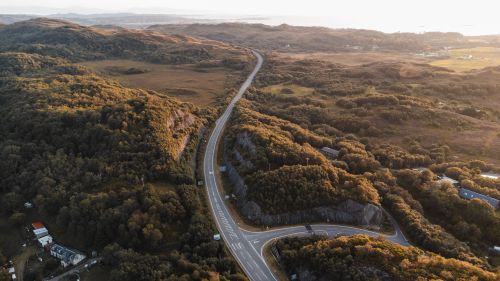 Free A stunning aerial view of a winding road through the lush highlands of Morar, Scotland at sunset. Stock Photo