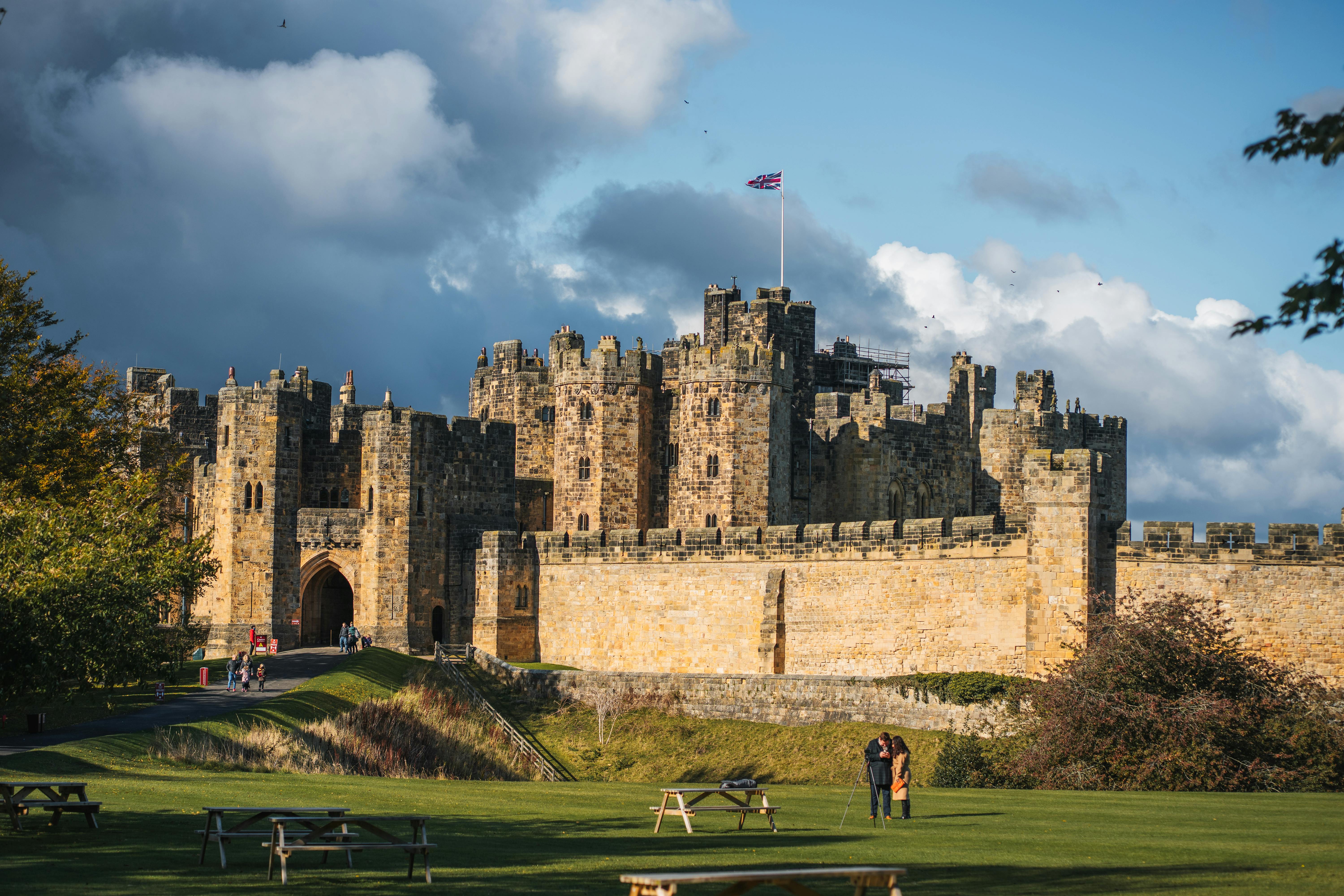 Explore the historic Alnwick Castle in England, captured under a stunning sky with autumn hues.