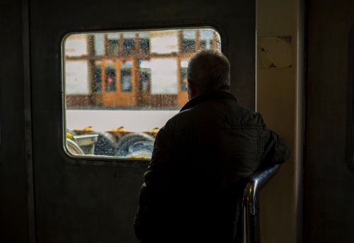 Free A senior adult man looks contemplatively through a rainy window, offering a sense of solitude. Stock Photo