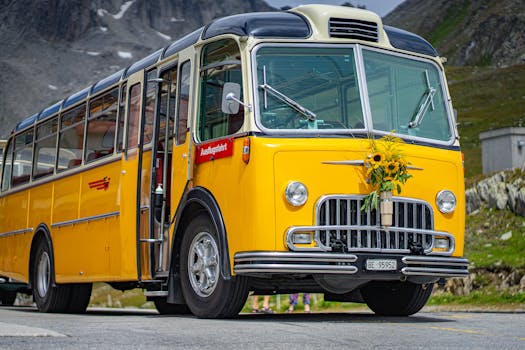 A classic yellow bus adorned with sunflowers parked in a mountainous outdoor setting.