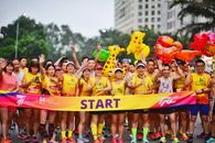 Cheerful runners at a 5K race start line holding colorful inflatable toys in a lively outdoor setting.