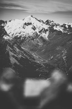 Snow-capped mountain range with winding road in a captivating black and white tone.