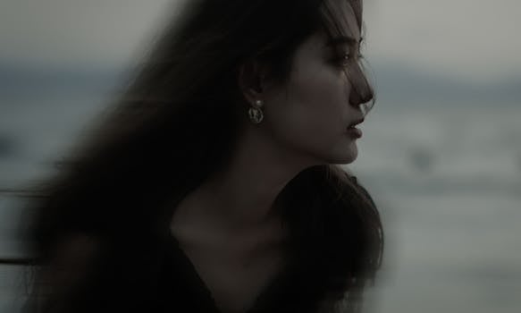 Side profile of a woman in low light, creating a dramatic moody atmosphere.