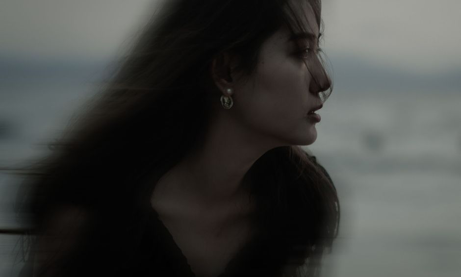 Side profile of a woman in low light, creating a dramatic moody atmosphere.