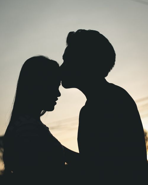 Free Silhouette of a couple sharing a tender moment with a kiss during a beautiful sunset. Stock Photo