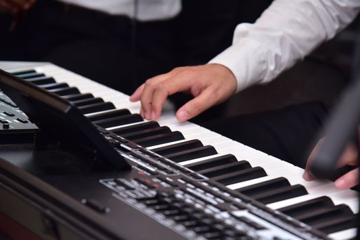 Musician's hands playing an electronic keyboard indoors, showcasing technique and precision.