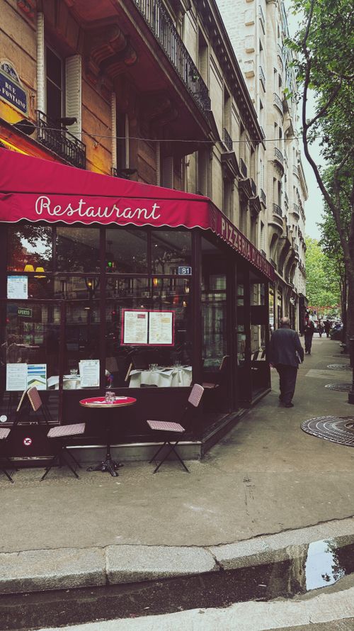 Free Discover the quintessential Parisian dining experience at this charming café with red awning and outdoor seating. Stock Photo