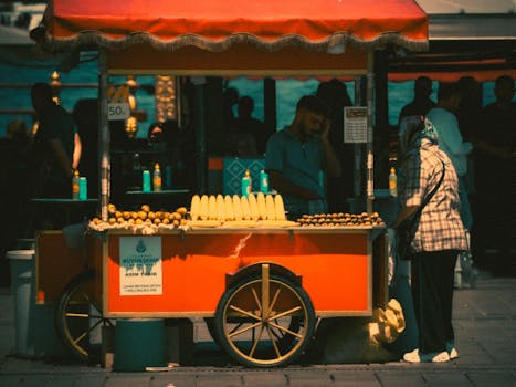 Colorful street vendor cart selling corn and chestnuts on a sunny day.