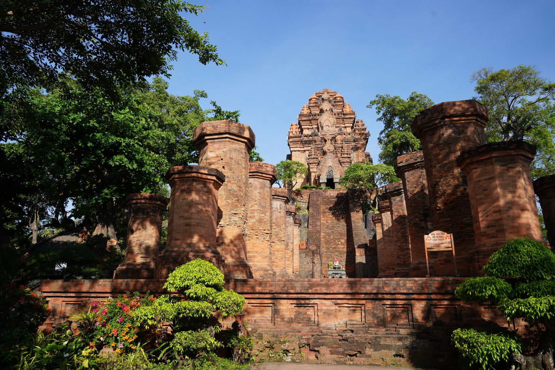 Capture of an ancient brick temple surrounded by trees under a clear blue sky.
