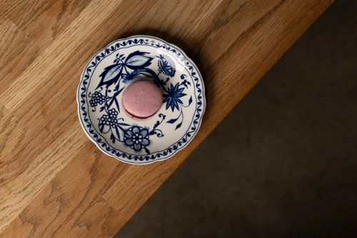 Free A delicious pink macaron sits on a traditional blue floral porcelain plate on a wooden table. Stock Photo
