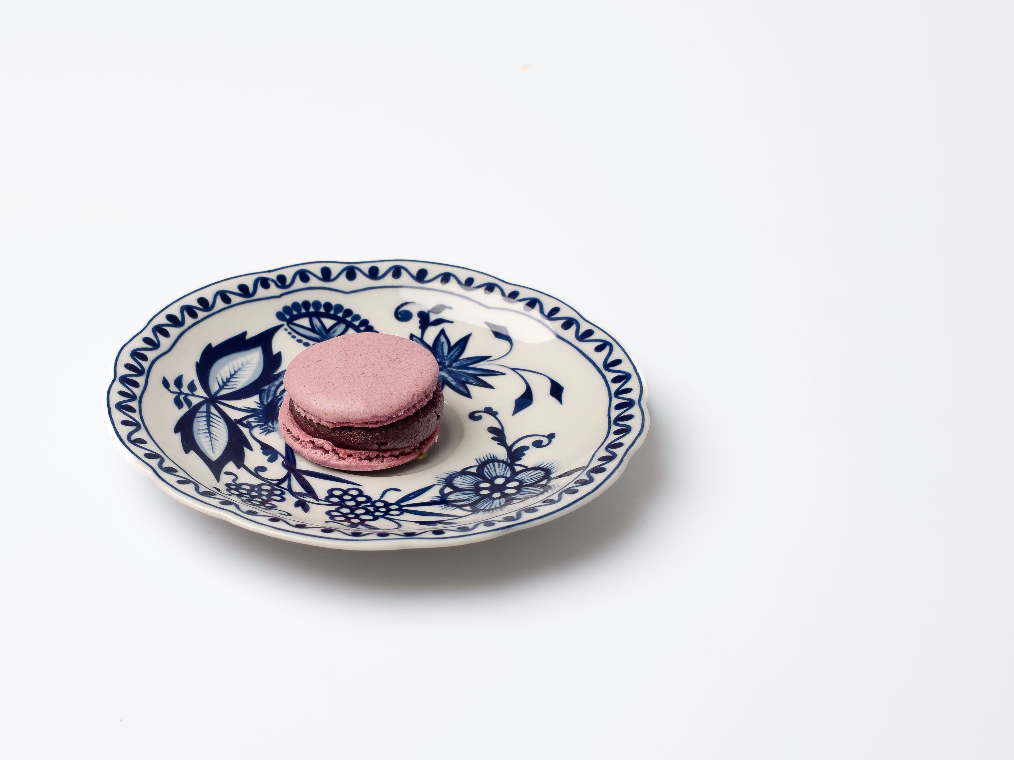 Artistic shot of a pink macaron on a classic blue and white floral plate. Perfect for food lovers. - Berlín