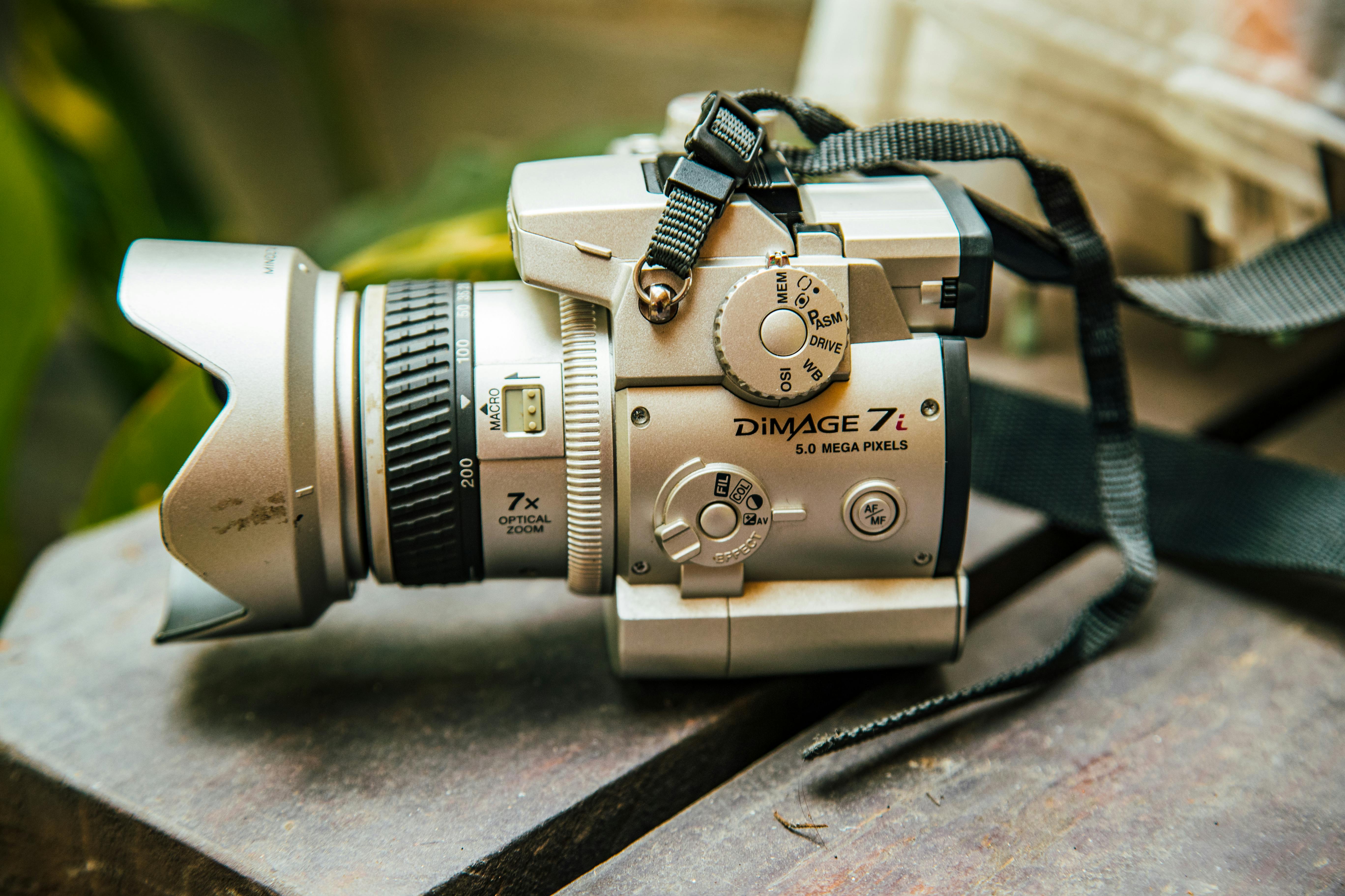 Free Close-up of a vintage silver camera resting on a wooden surface with a strap attached. Stock Photo