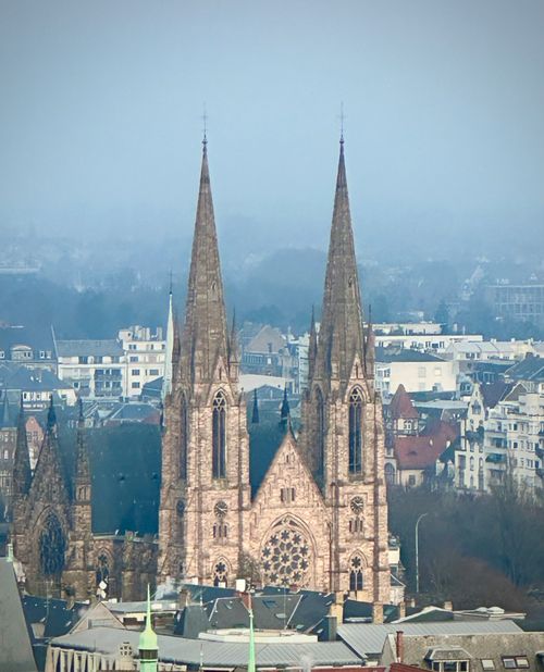 Free Majestic Gothic cathedral spires rise above a misty cityscape at dawn for a serene view. Stock Photo