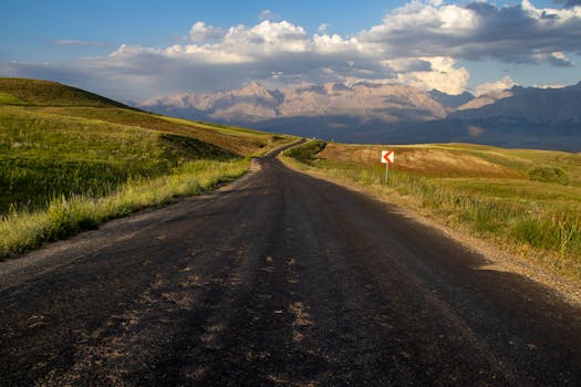 Scenic road leading towards distant mountains under clear skies, showcasing nature's beauty.