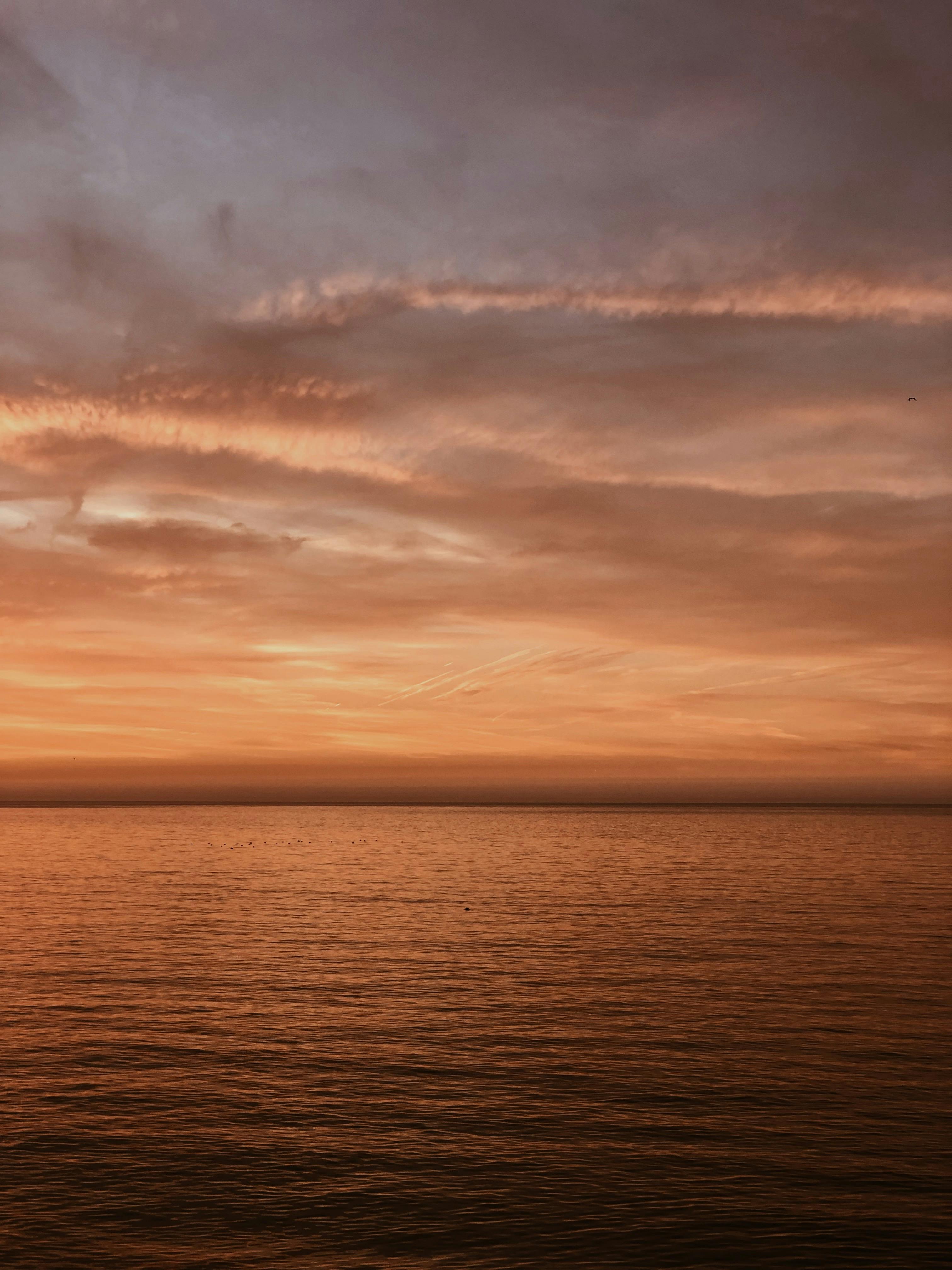 A tranquil ocean sunset with vibrant golden and orange hues in the sky.