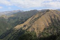 Majestic mountain landscape featuring lush valleys and rugged peaks under a clear blue sky.