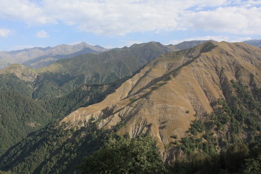 Majestic mountain landscape featuring lush valleys and rugged peaks under a clear blue sky.