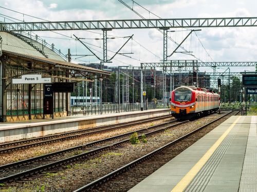 Free Orange train at an empty station platform with overhead wires. Stock Photo