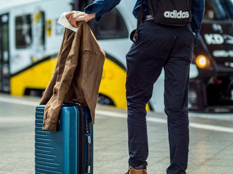 Traveler with suitcase waiting at train station platform.