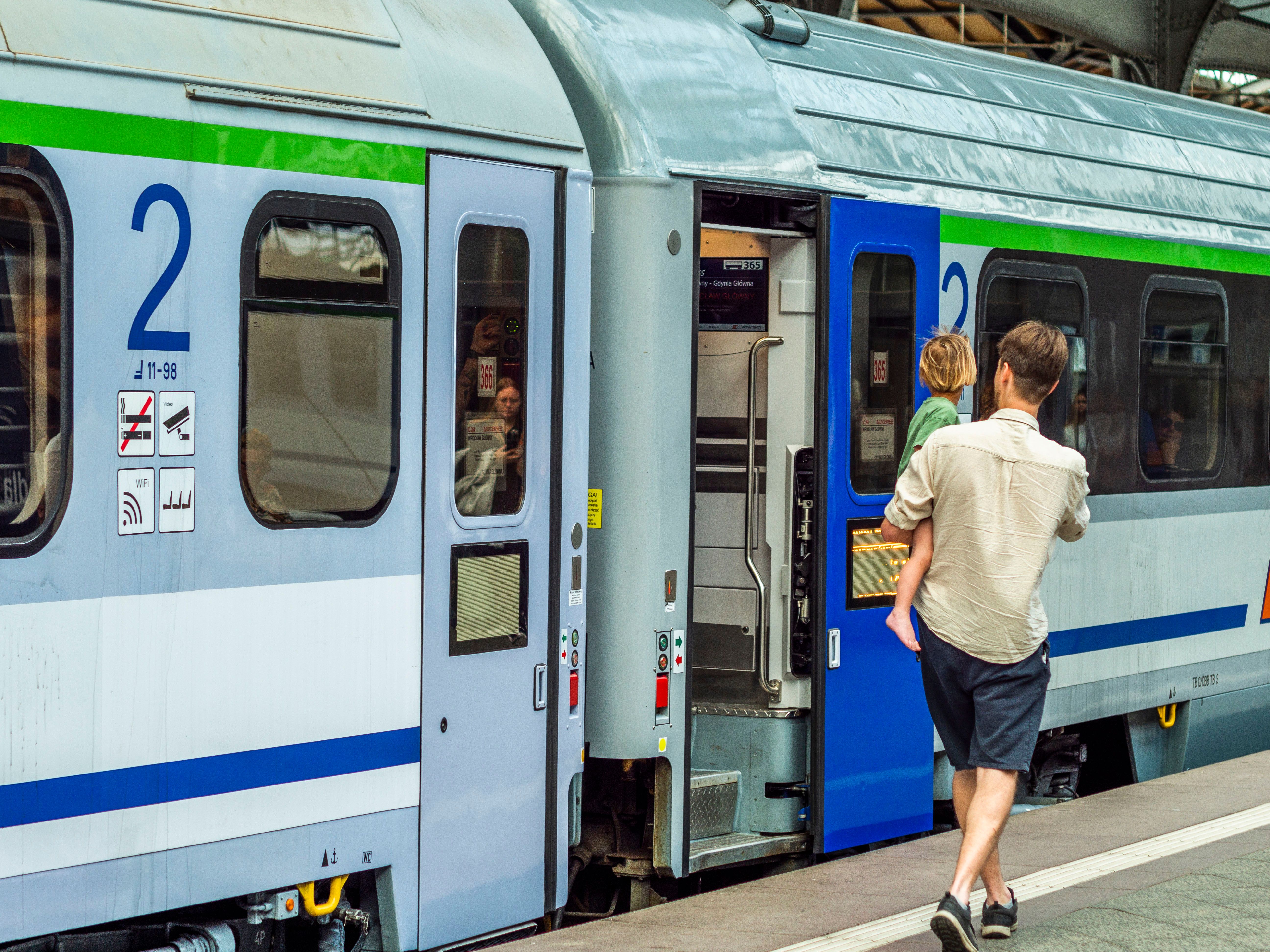 Adult male with child boarding train at railway station. Urban travel scene.