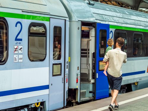 Free Adult male with child boarding train at railway station. Urban travel scene. Stock Photo