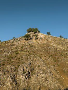 Scenic view of rocky hill landscape with green trees against a clear blue sky in Elazığ, Türkiye.