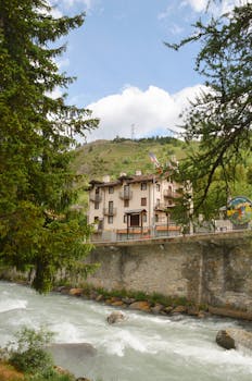 Picturesque mountain house in Valle d'Aosta, Italy by a vibrant river in summer.