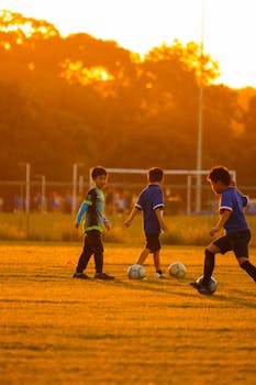 Kids enjoying a game of soccer outdoors during sunset, fostering teamwork and fun.