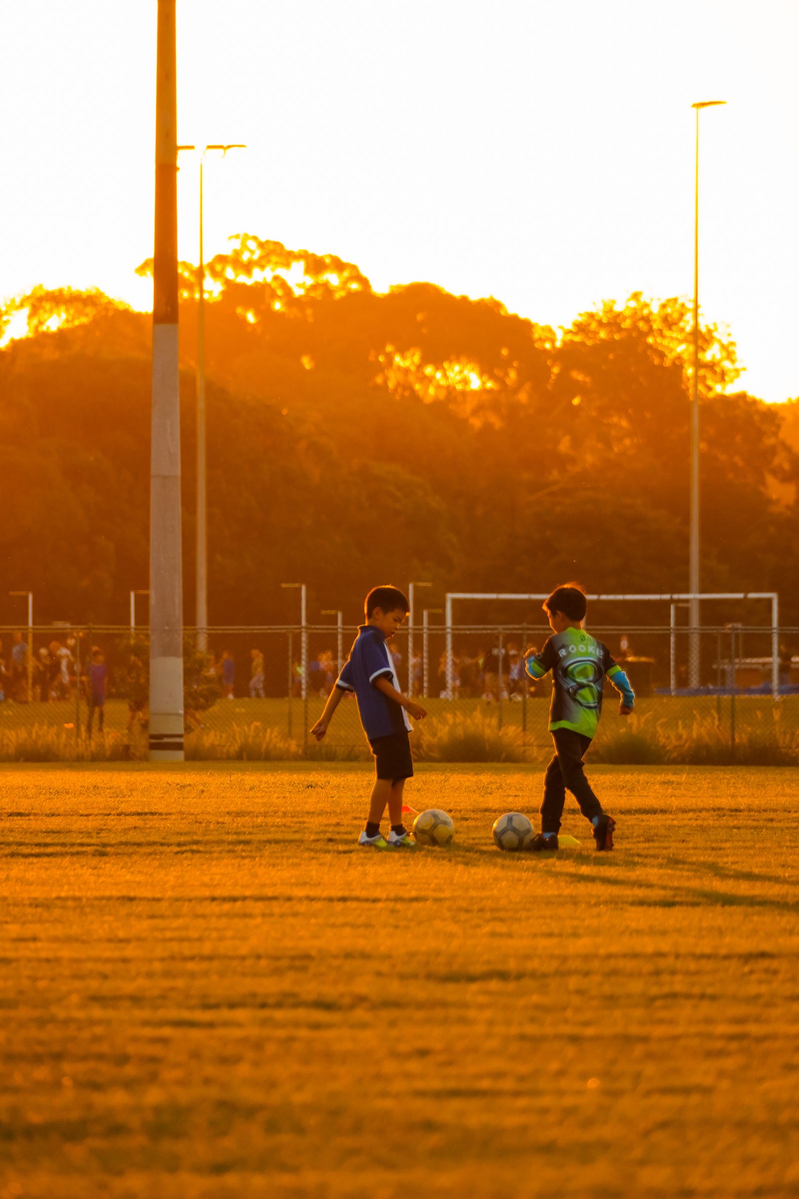 Two young soccer players on the field at sunset