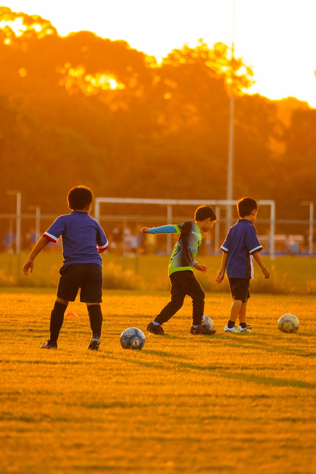 Children playing soccer at sunset during outdoor games for kids