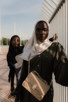 Striking portrait of two stylish Nigerian women in hijabs, showcasing elegance and confidence outdoors.