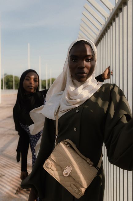 Striking portrait of two stylish Nigerian women in hijabs, showcasing elegance and confidence outdoors.