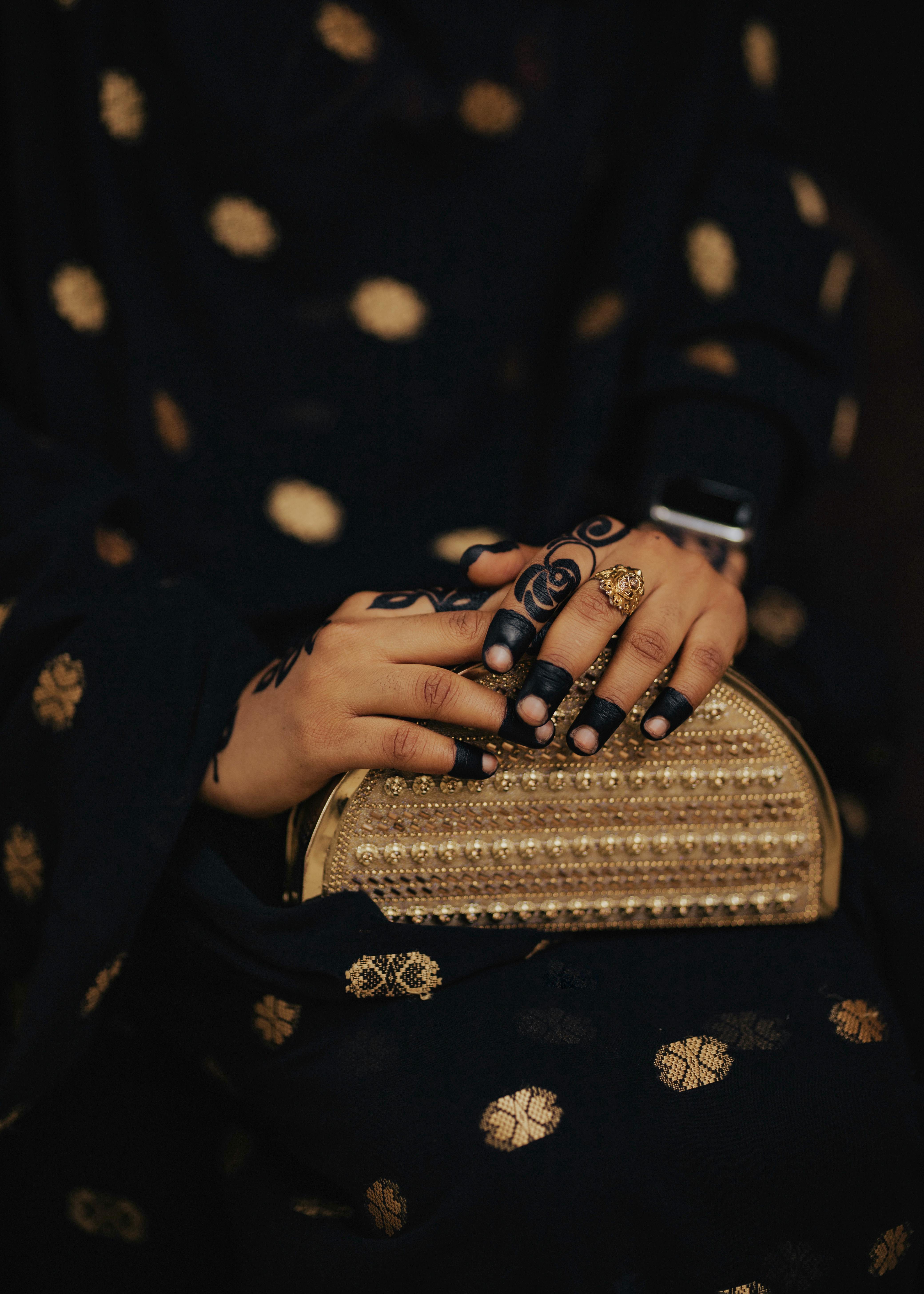 Gratis Primo piano di mani decorate con l'henné che tengono una pochette di perline, simbolo di eleganza tradizionale. Foto a disposizione