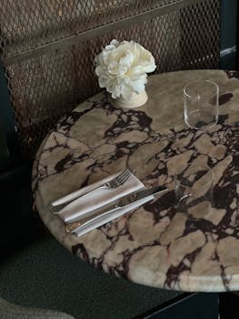 Marble table setup with white flowers and cutlery, creating an elegant dining ambiance.