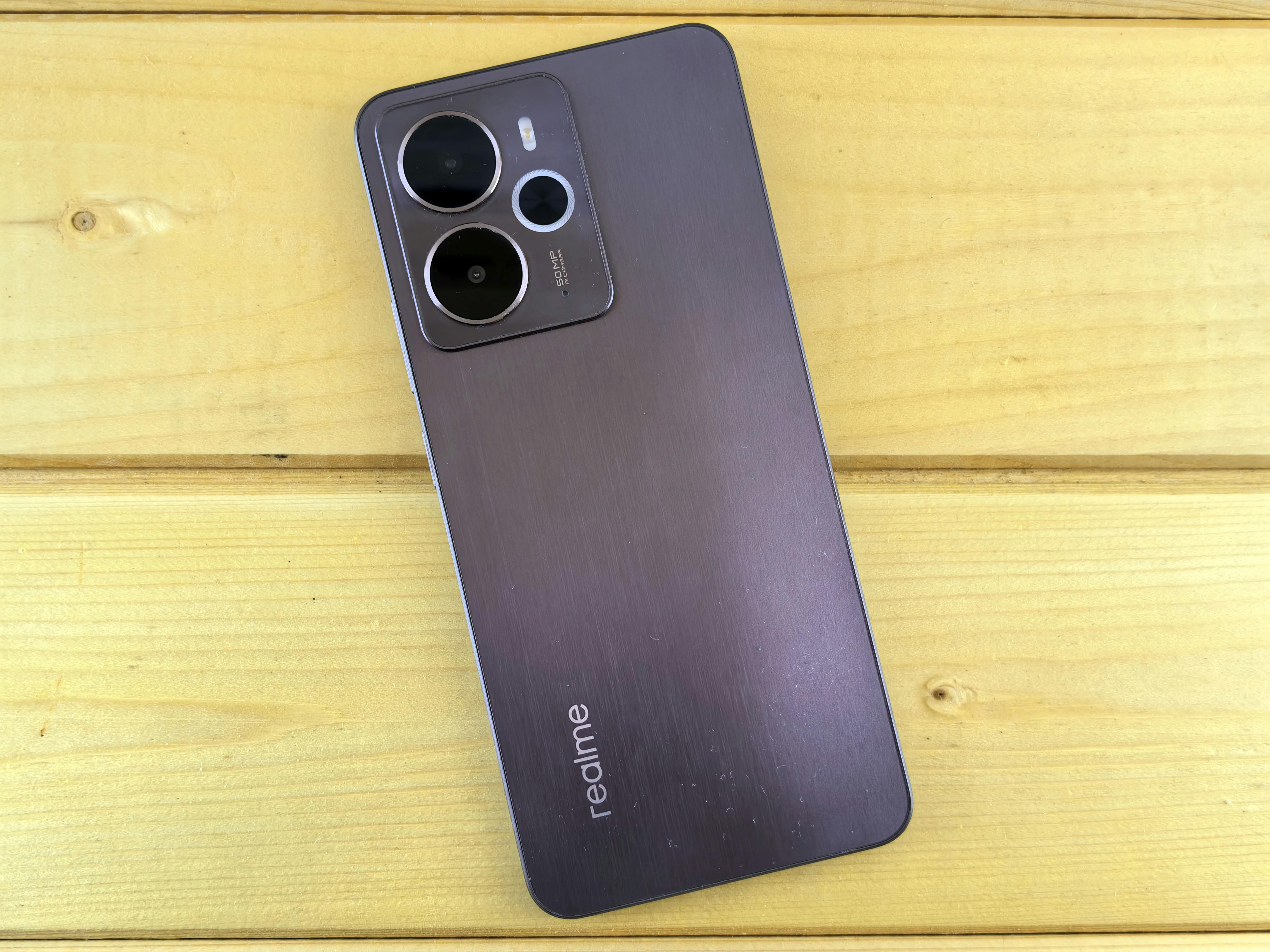 Modern smartphone with dual cameras displayed on a wooden surface, showcasing technology design.