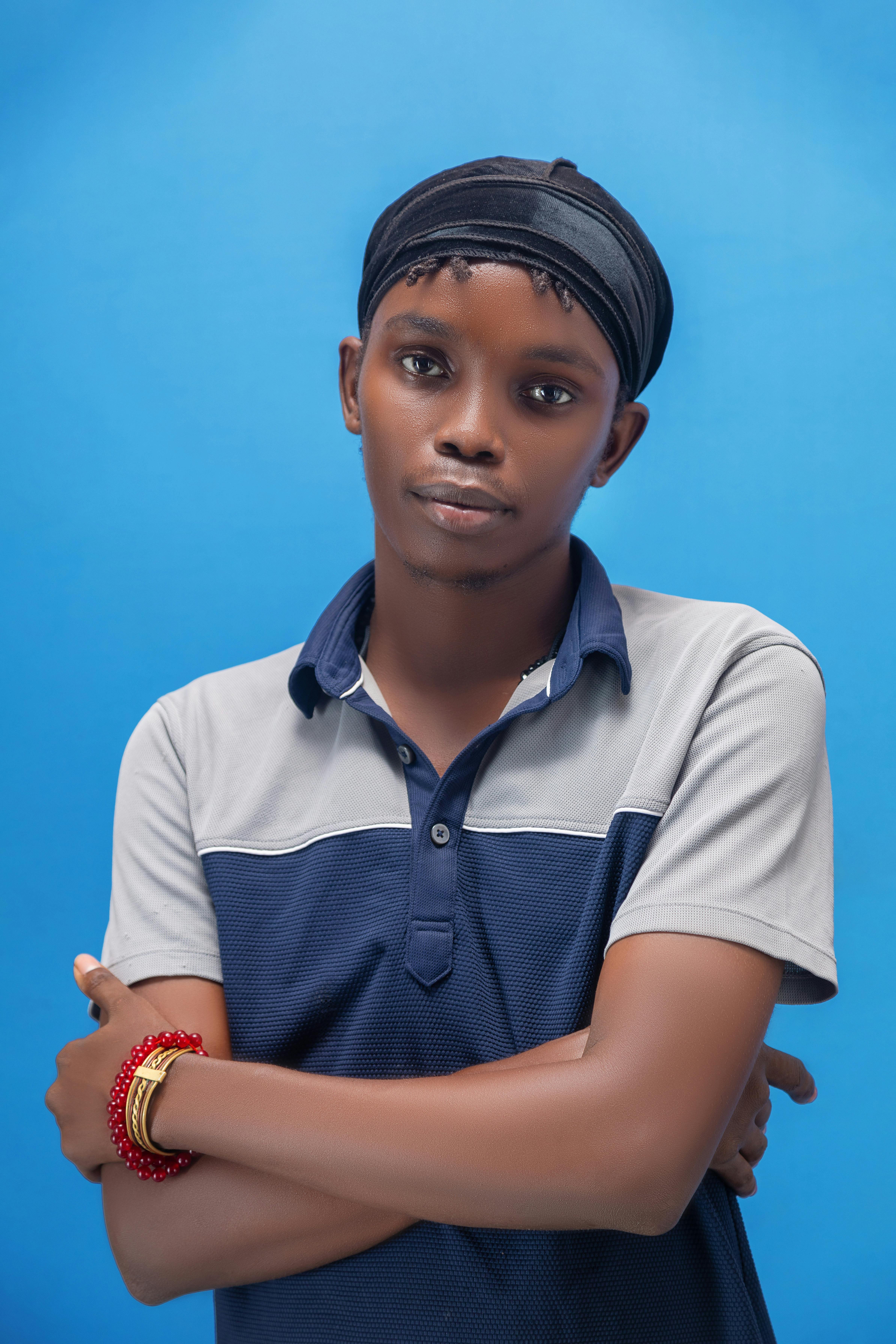 grátis Retrato elegante de um jovem negro com pulseiras e lenço na cabeça contra um fundo azul. Foto profissional