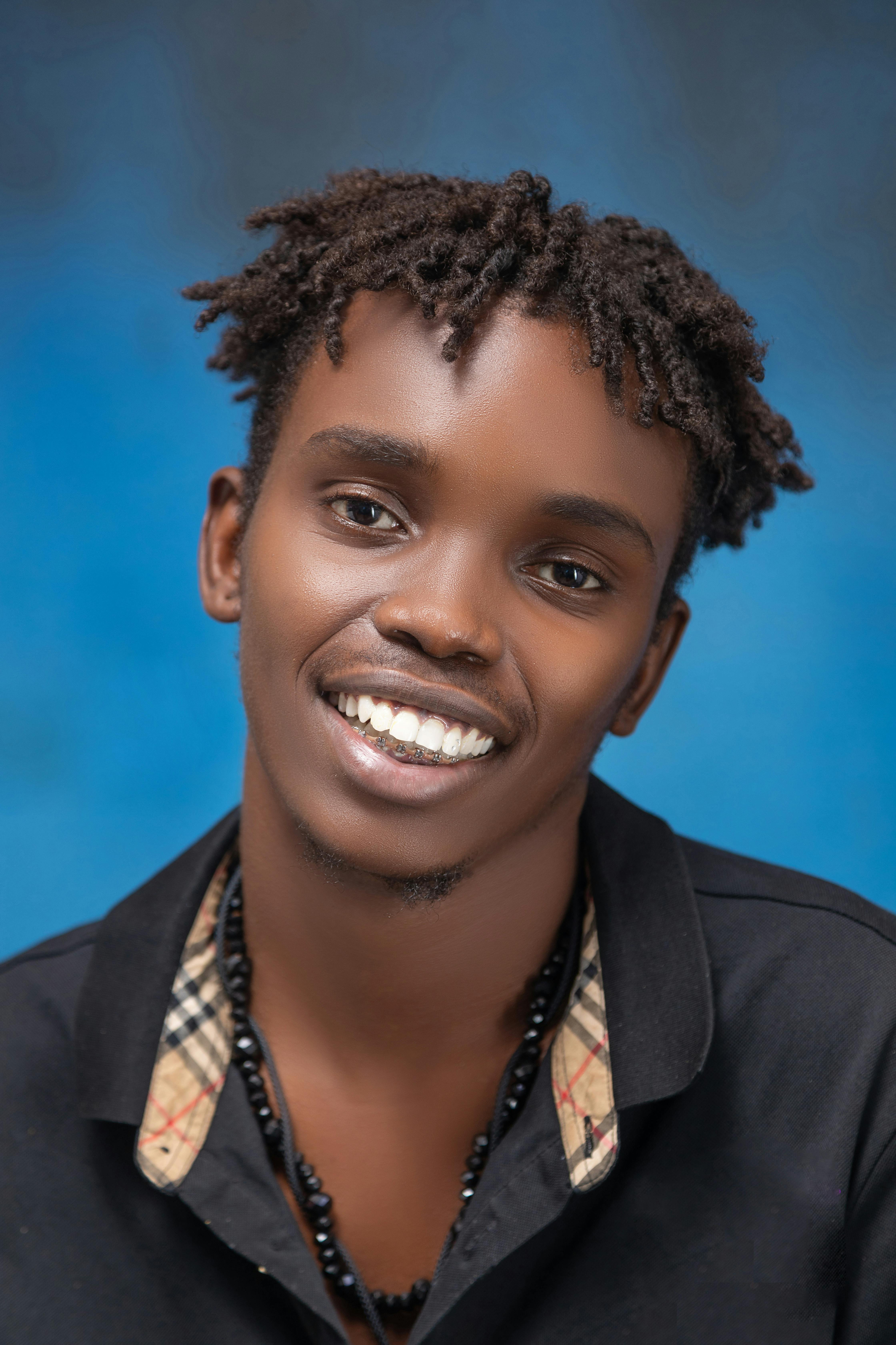 grátis Retrato vibrante de um jovem adulto sorridente contra um fundo azul brilhante, exibindo uma expressão alegre. Foto profissional