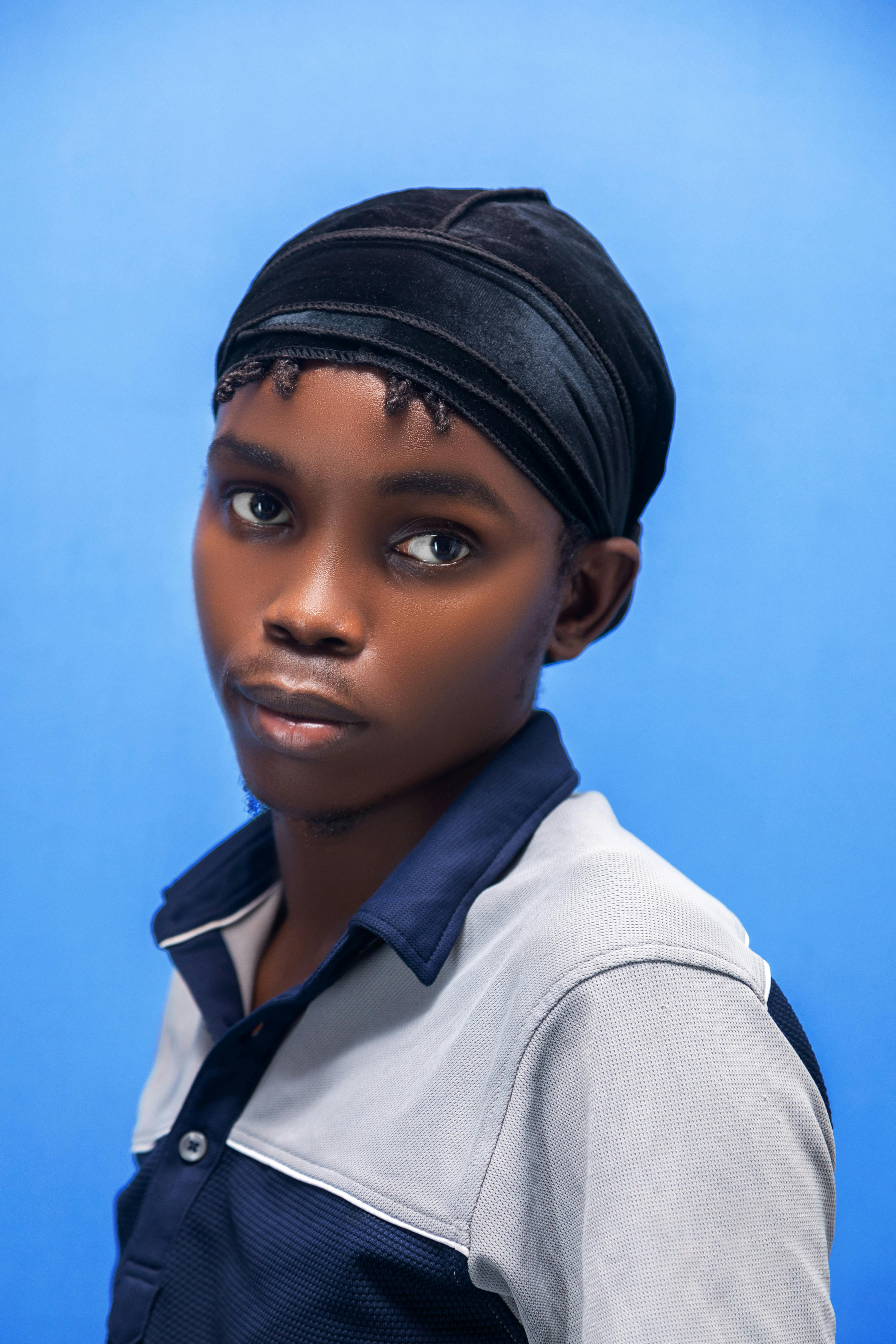 Gratis Un joven negro con un do-rag posando sobre un fondo azul vibrante, exudando un estilo moderno y seguro. Foto de stock