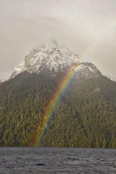 Majestic rainbow arches over snow-capped Nahuel Huapi mountain in Argentina.