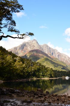 Stunning view of a tranquil lake reflecting a majestic mountain under a clear blue sky.