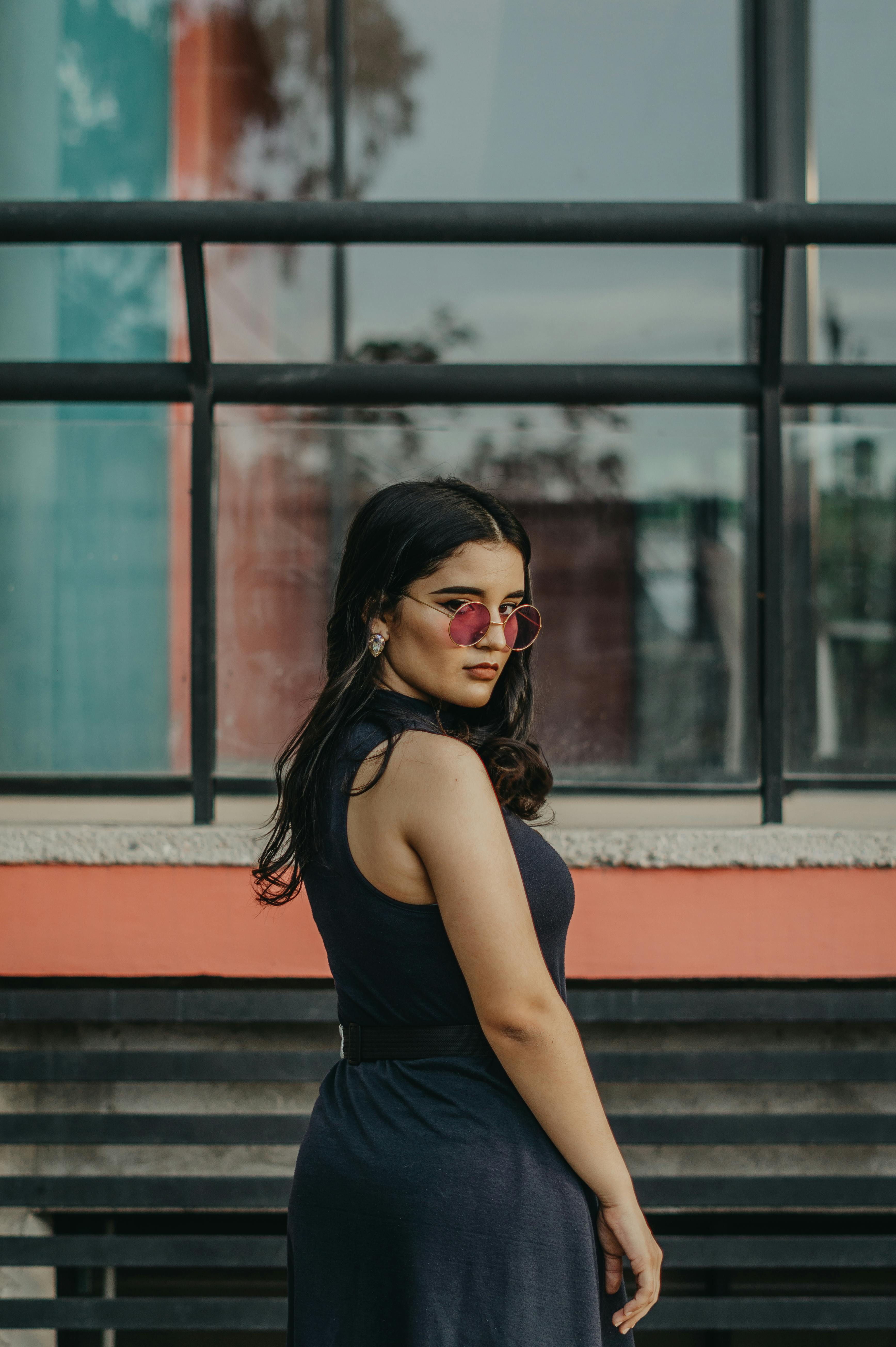 一位时尚的年轻女子戴着太阳镜，在城市建筑外摆姿势的肖像