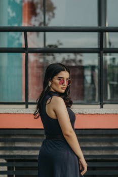 一位时尚的年轻女子戴着太阳镜，在城市建筑外摆姿势的肖像