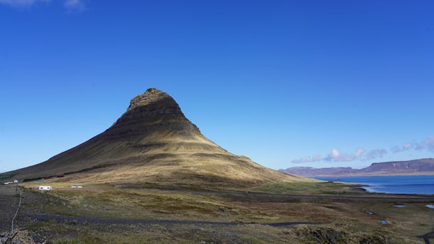 Scenic view of Kirkjufell with clear blue sky in Iceland's dramatic landscape.