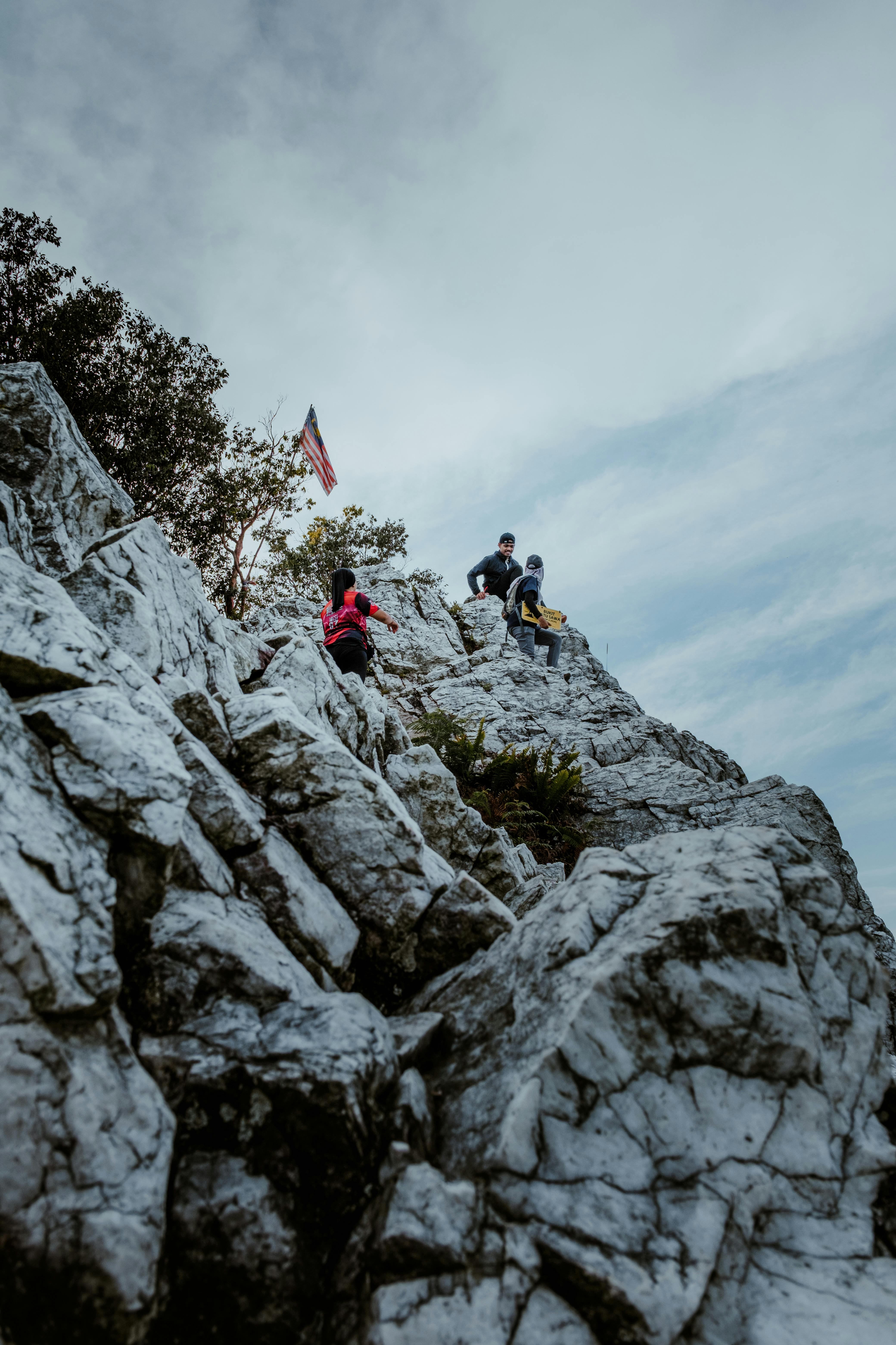 A person climbing a mountain and reaching the summit with a flag.