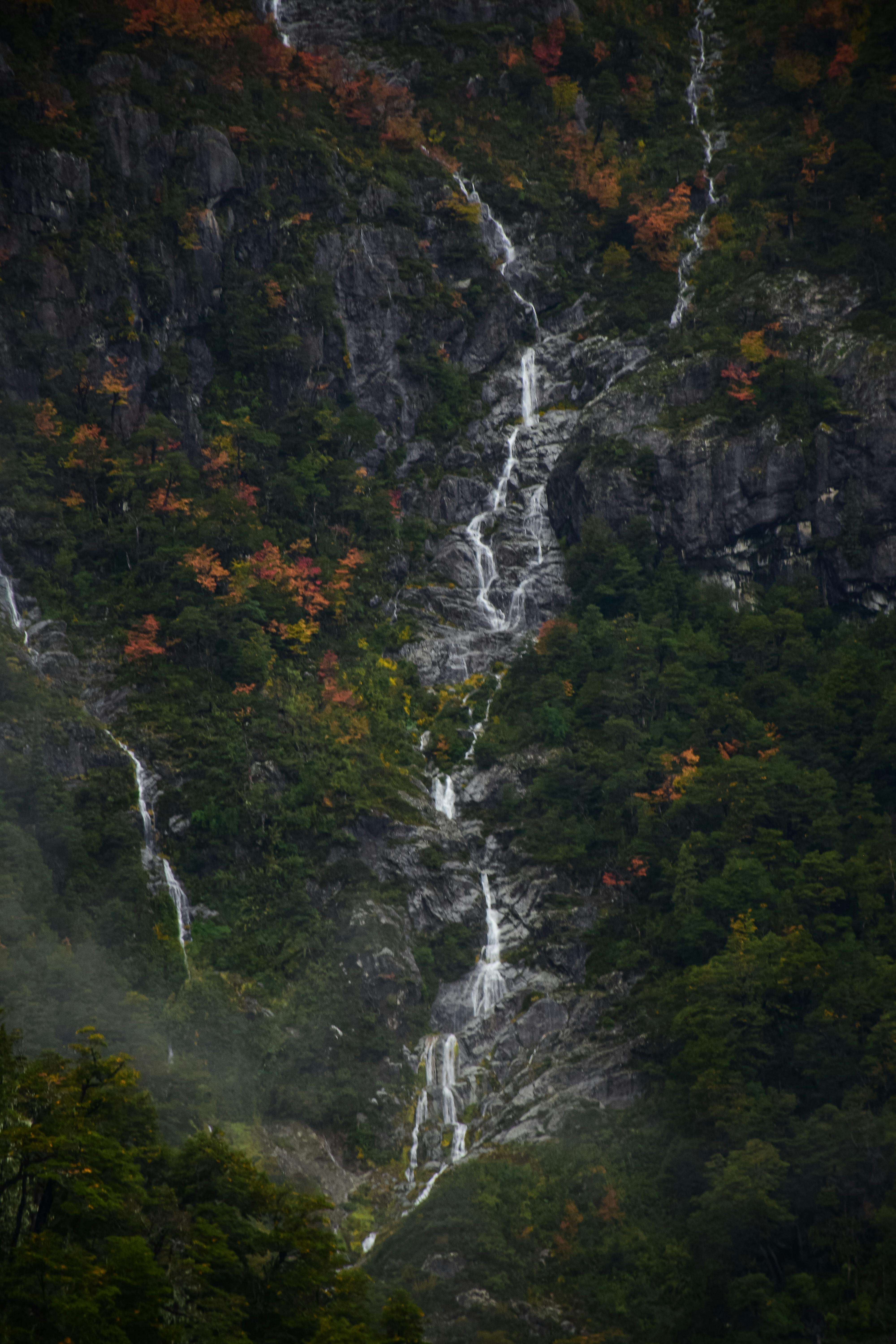 A stunning mountain waterfall cascading through an autumn forest with vibrant colors.