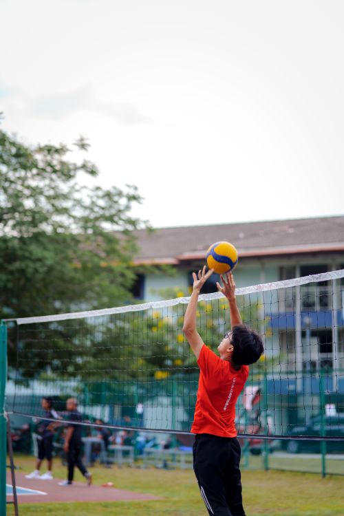 Free A teenager jumps to hit a volleyball over a net in an outdoor sports game. Stock Photo